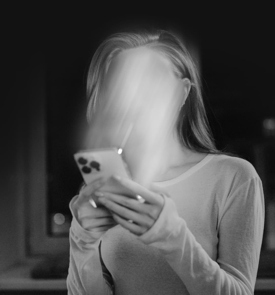 black and white distorted photo of a woman looking at her phone